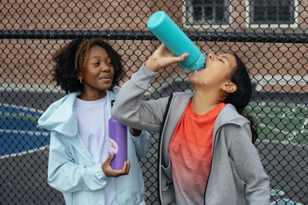 Enfants avec des gourdes d'eau après une séance de sport